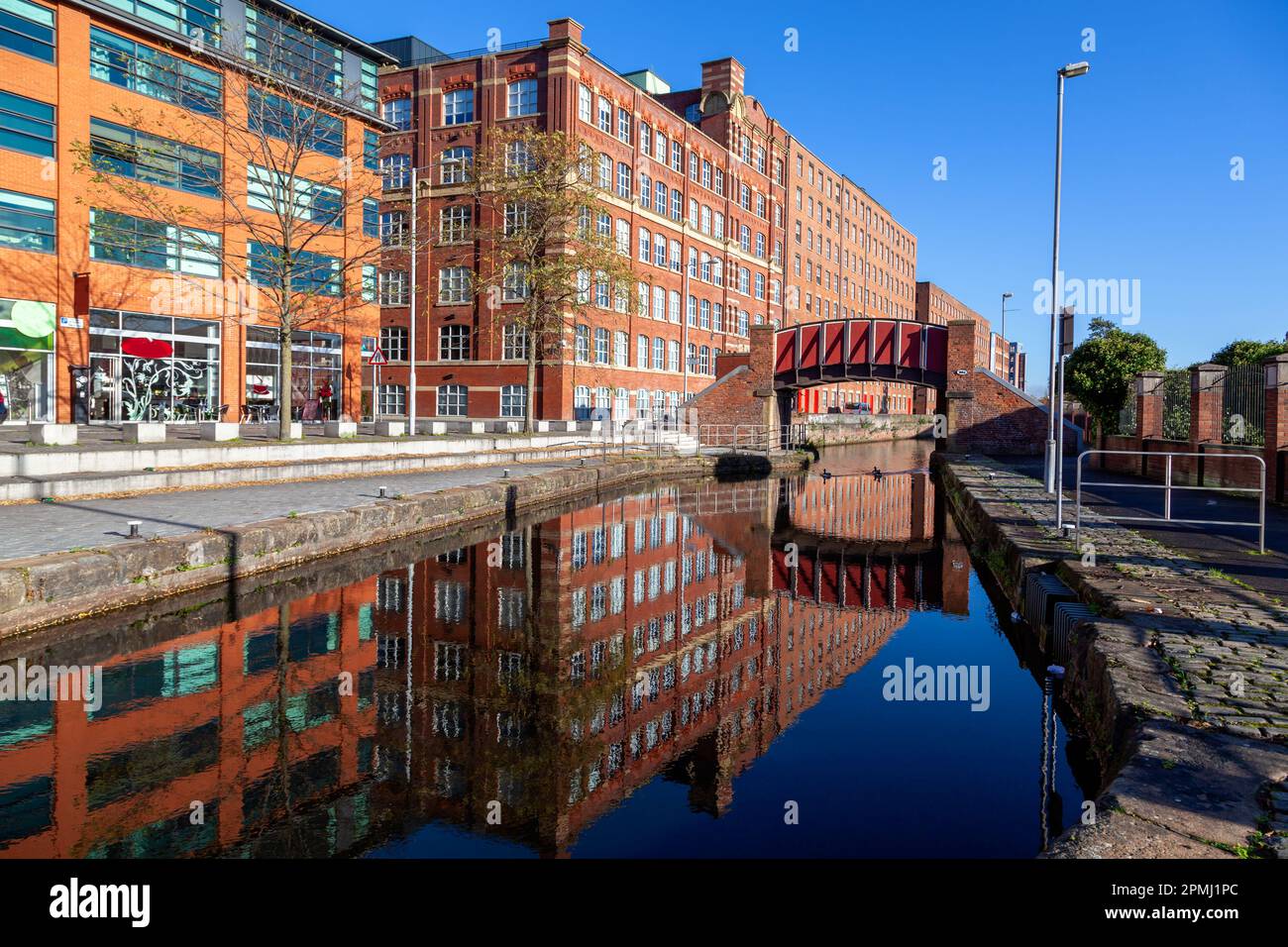 Reflection of Footbridge and warehouses  in Murray Mills Redhill Street Ancoats Manchester UK Stock Photo