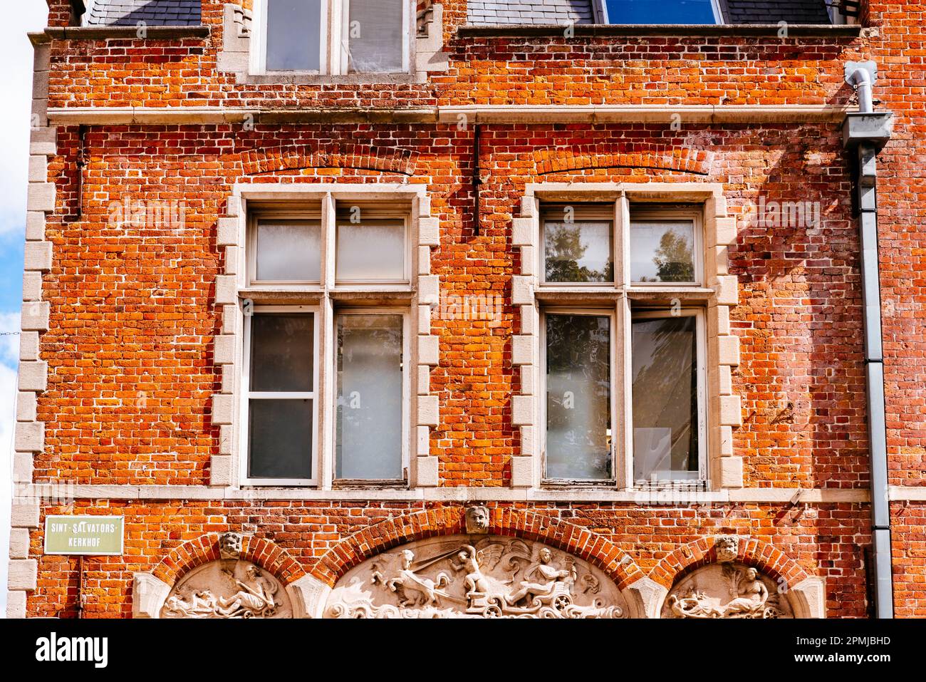 Detail of house facade with red bricks and bas relief. Bruges, West