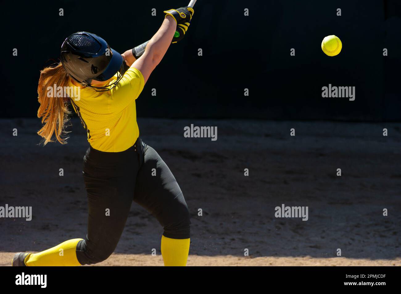 A Baseball Softball Player Is Swinging And Hitting The Ball Stock Photo