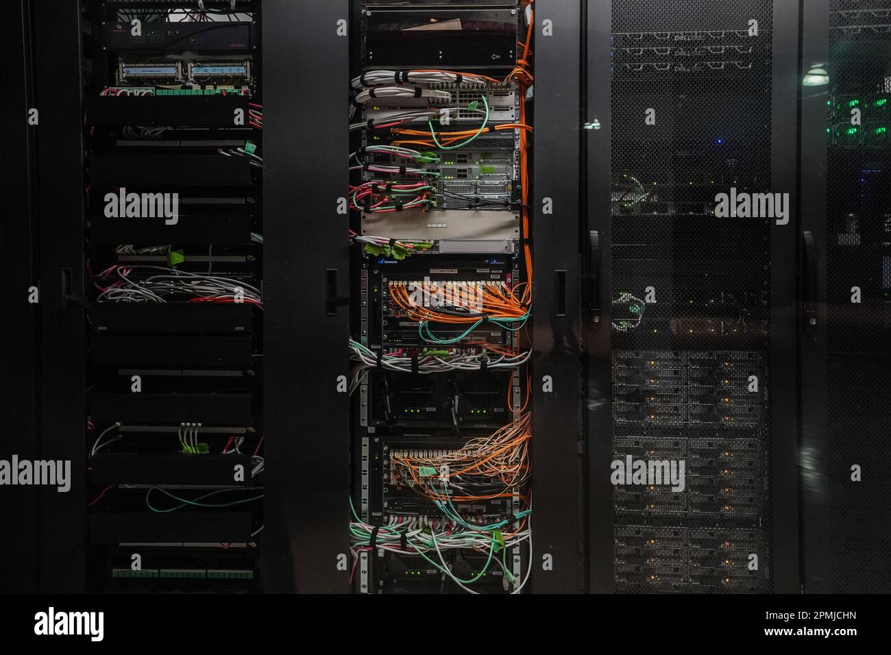 Network and power cables behind racks of computer servers inside a secure data center room Stock