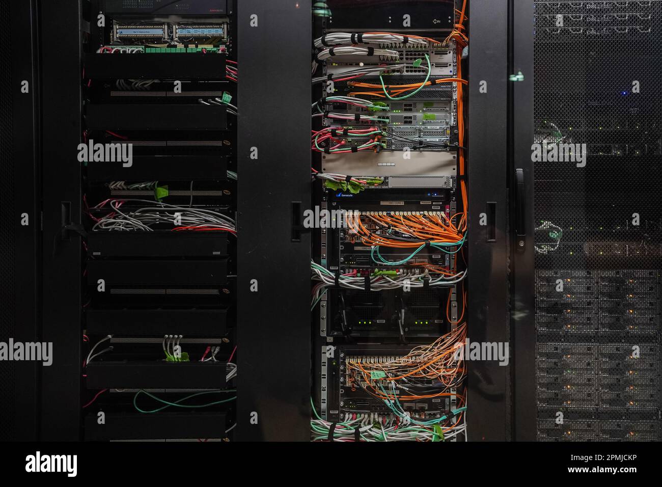 Network and power cables behind racks of computer servers inside a ...