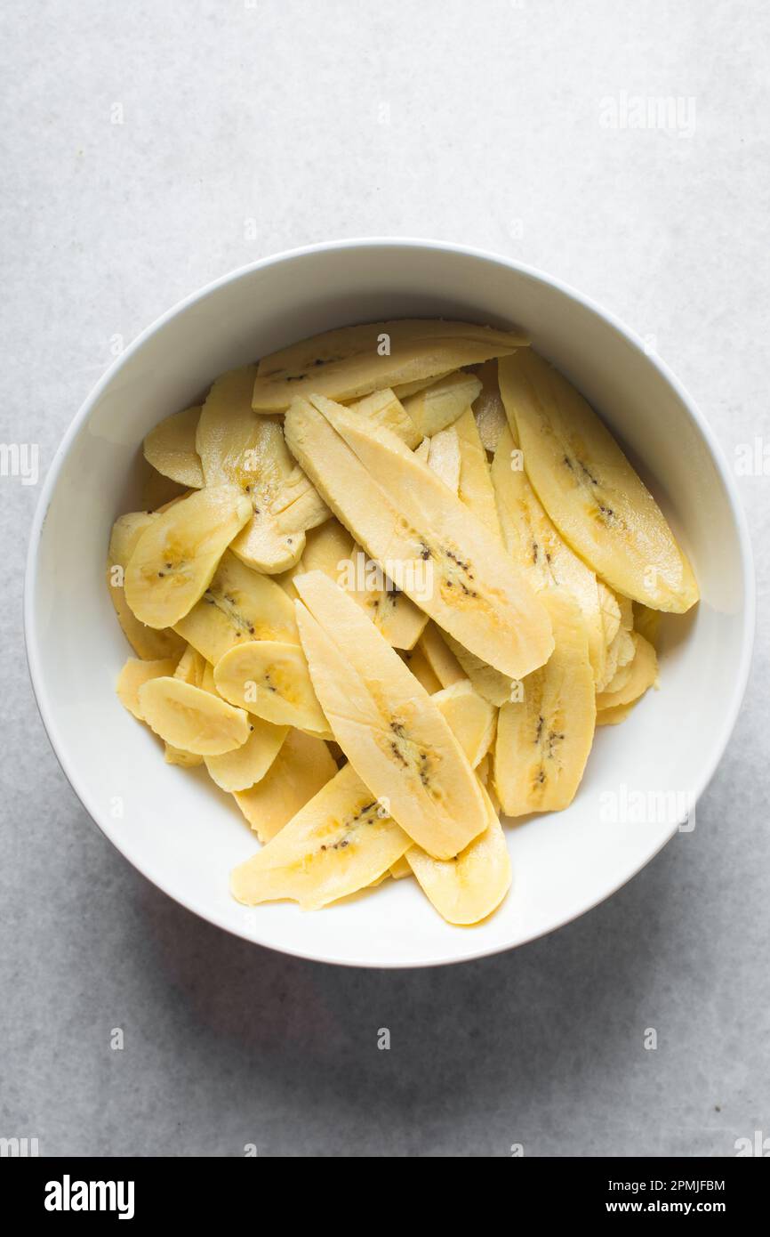 slices of ripe plantains in a white bowl, slices of yellow plantains