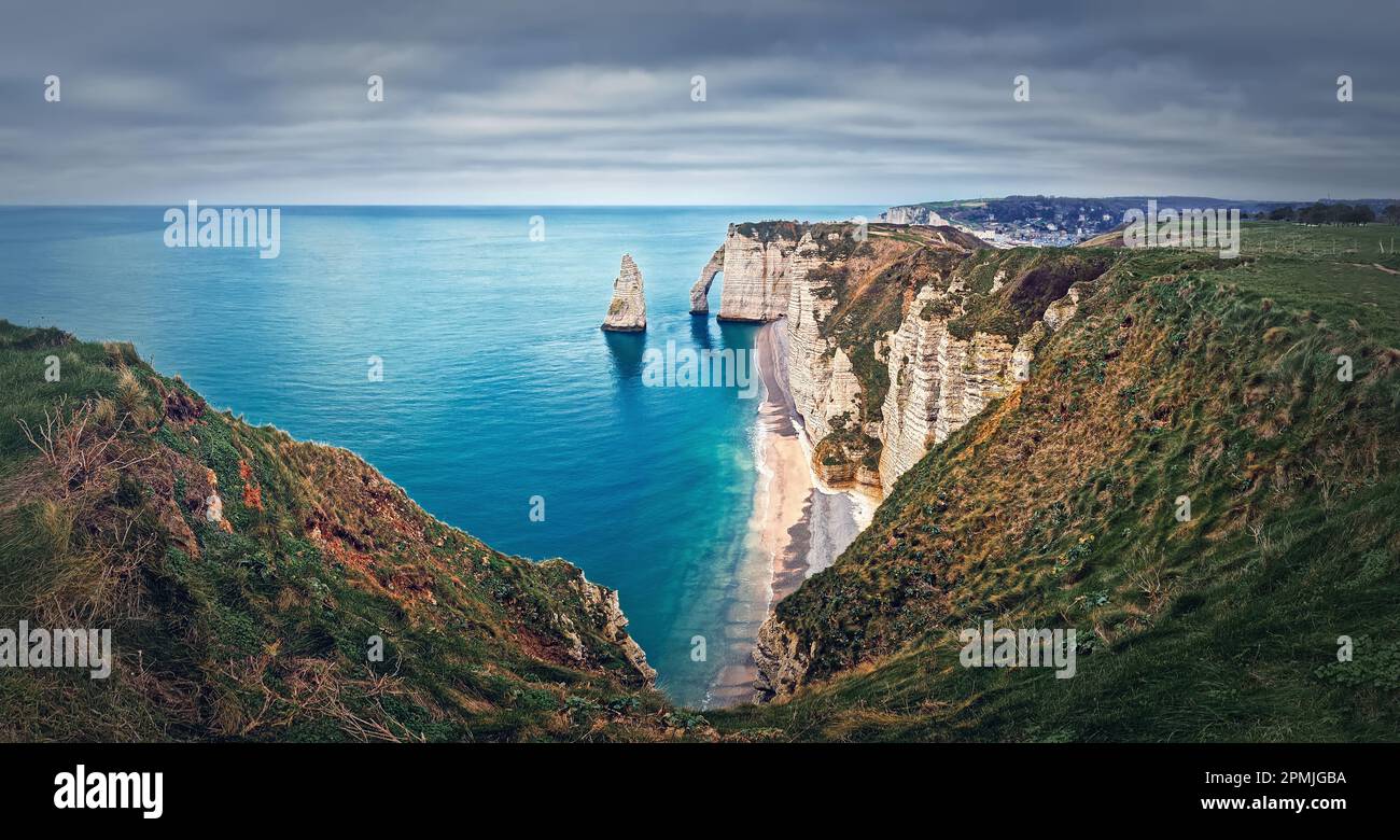 Falaise d'Aval limestone cliffs washed by La Manche channel waters. Beautiful coastline panorama with view to the famous rock Aiguille of Etretat in N Stock Photo
