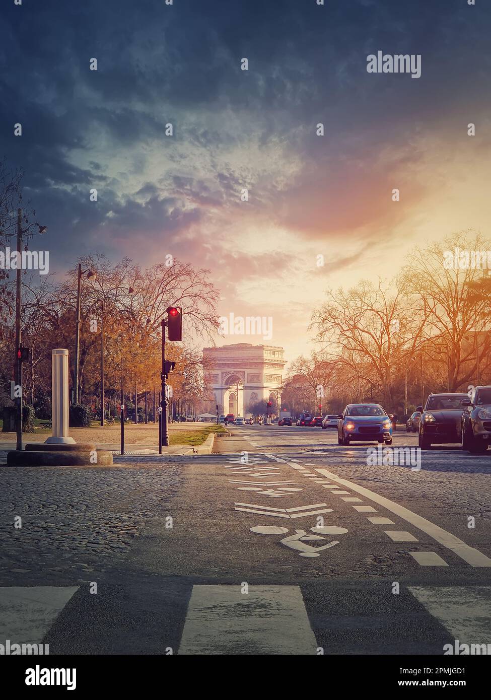 Triumphal Arch (Arc de triomphe) in Paris, France. The famous historic landmark in sunset light seen from the city street with busy traffic Stock Photo