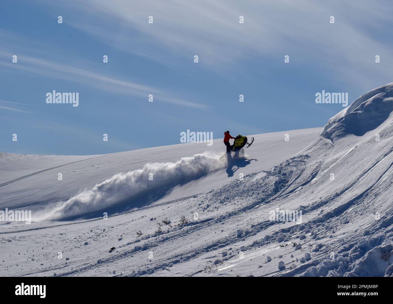 A man is riding snowmobile in mountains. Beautiful day in Swedish Lapland. Kiruna, Nikkaluokta. Stock Photo