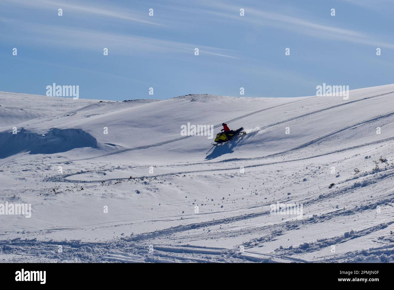 A man is riding snowmobile in mountains. Beautiful day in Swedish Lapland. Kiruna, Nikkaluokta. Stock Photo