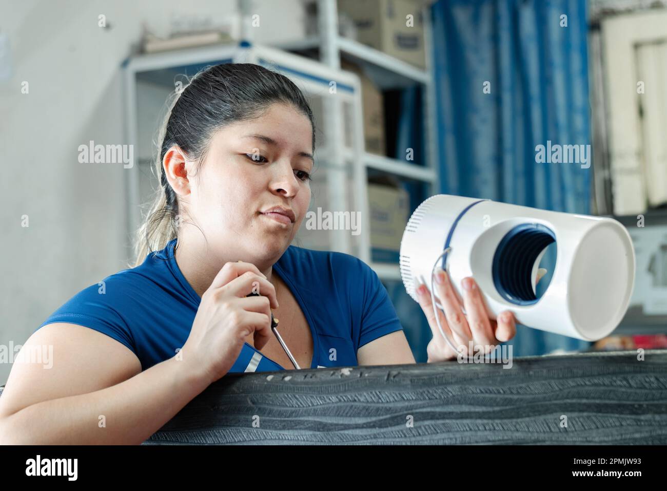 young latina woman watching attentively how an automatic mosquito catcher works Stock Photo