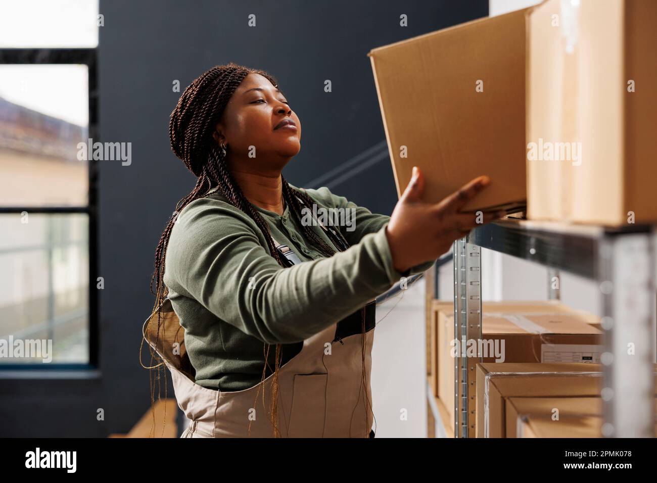African american worker putting cardboard boxes on metallic shelves ...