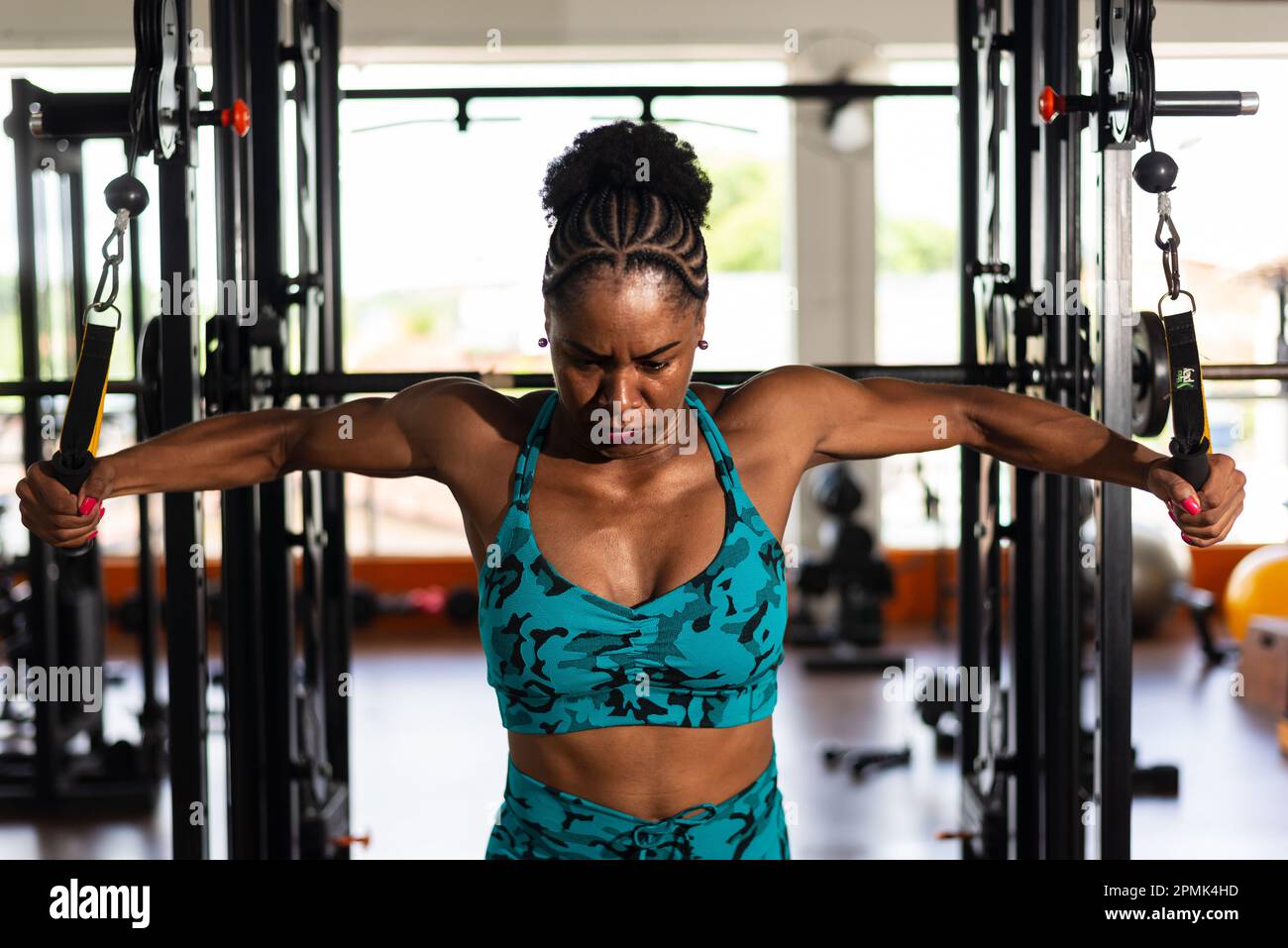 Muscular woman doing arm exercises on a machine at the gym. Determination  and focus Stock Photo - Alamy