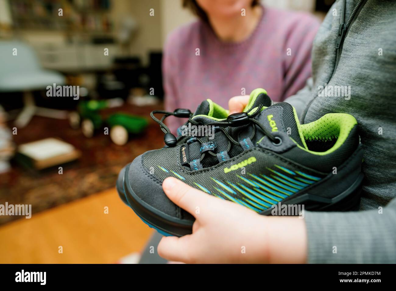 Frankfurt, Germany - Mar 12, 2023: A child showing modern, stylish Lowa  boots with vibrant blue and green design. Waterproof and insulated for  warmth in cold winter conditions - mother in background Stock Photo - Alamy