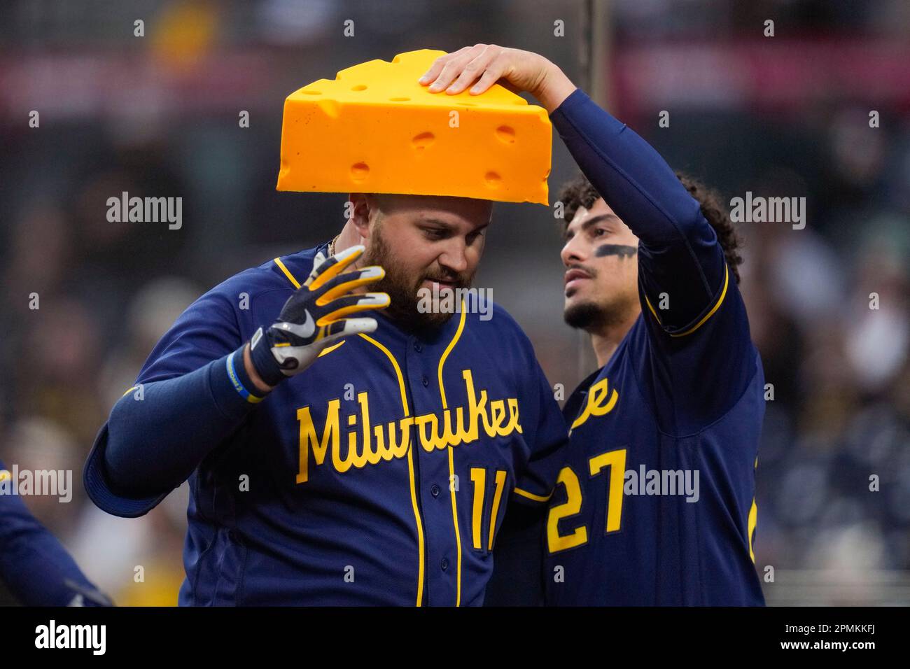 Milwaukee Brewers' Willy Adames, right, places a cheesehead hat on