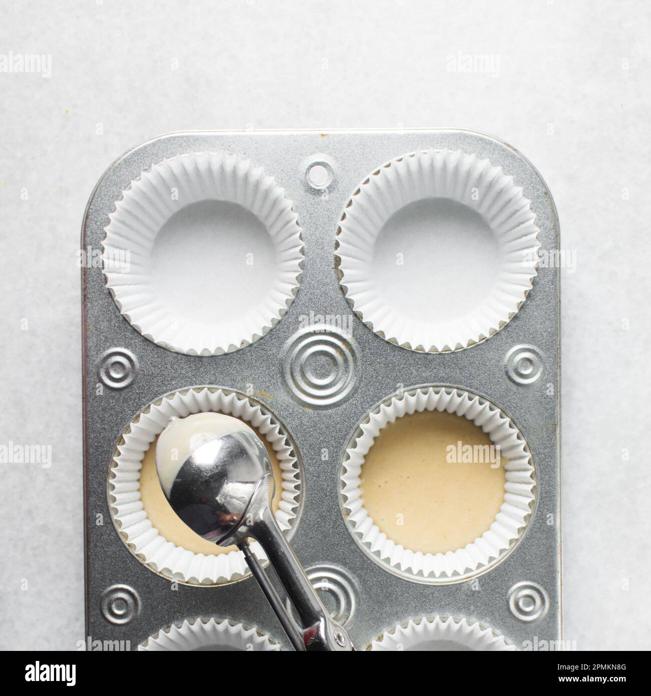 Hand scooping vanilla cake batter into a cupcake tin, An ice cream