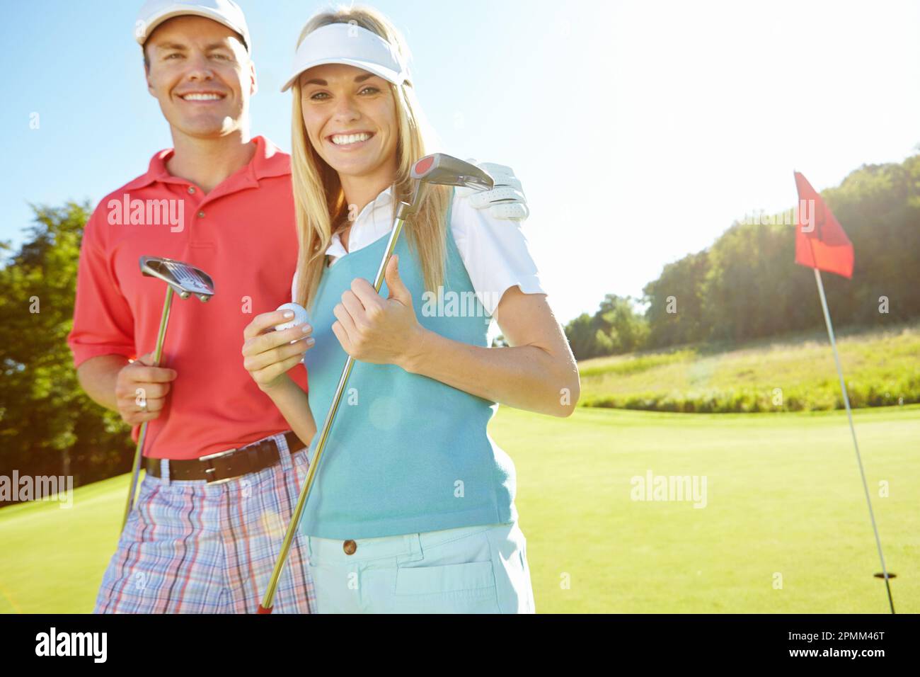 Tee time. Attractive young couple with their golf clubs and balls on