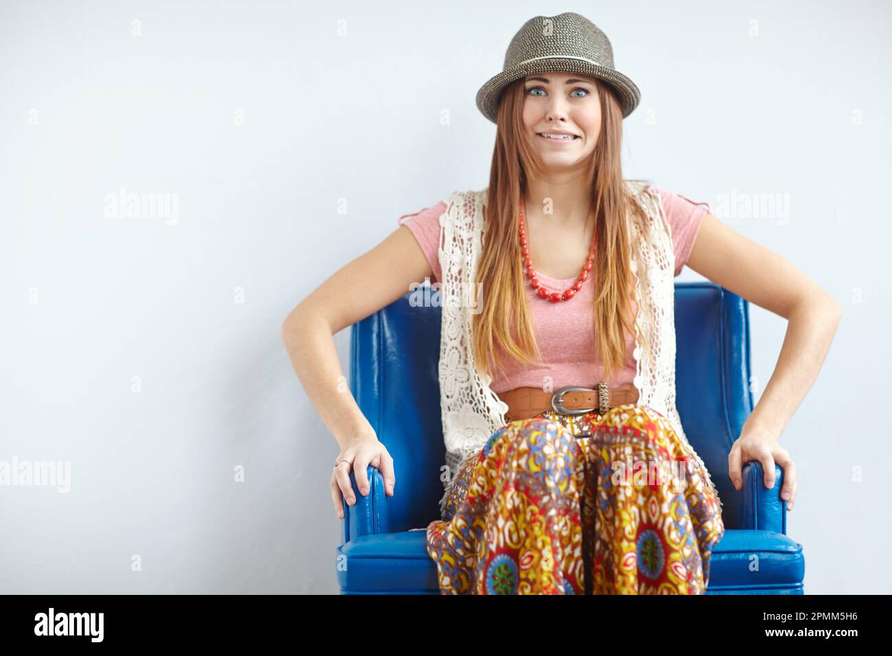Portrait of a quirky woman in vintage clothing on a blue armchair