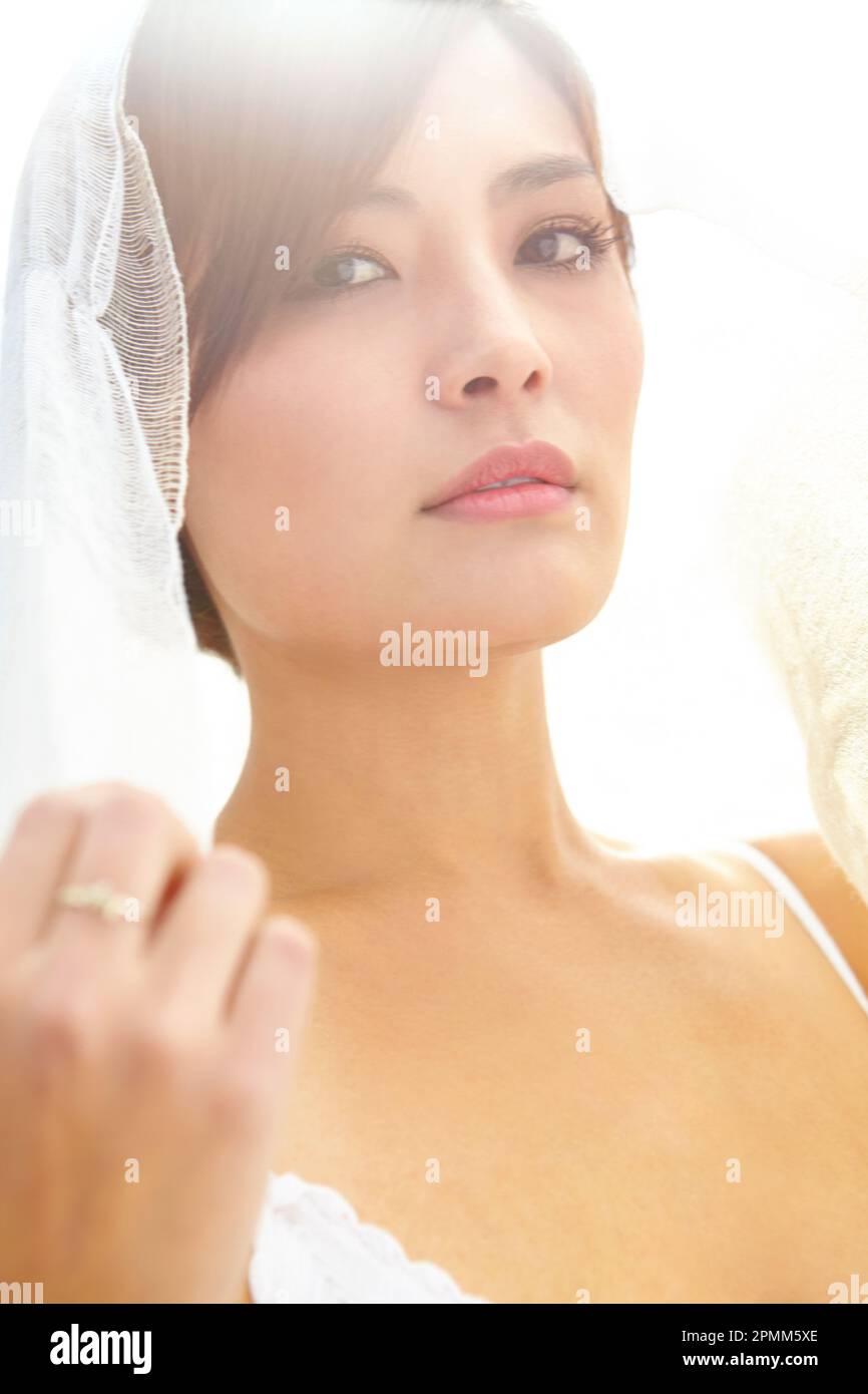 Veiled in romance. A beautiful young Asian bride wearing a lace veil. Stock Photo