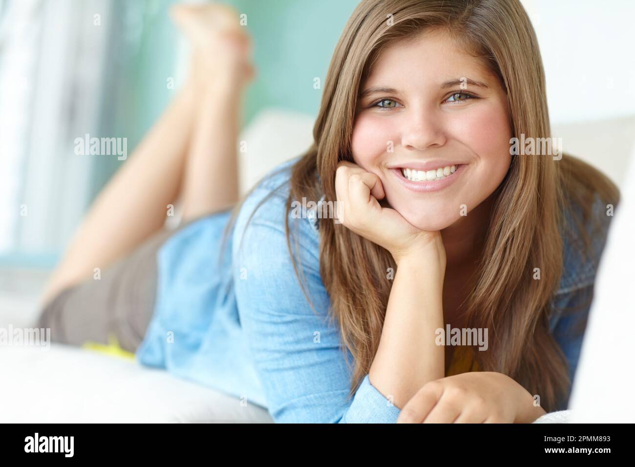 Just chilling on the couch. A pretty teenager relaxing on the couch happily. Stock Photo