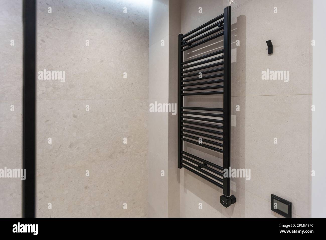 Modern and stylish black heated towel rail with thermostat. Metal heated towel rail on the wall