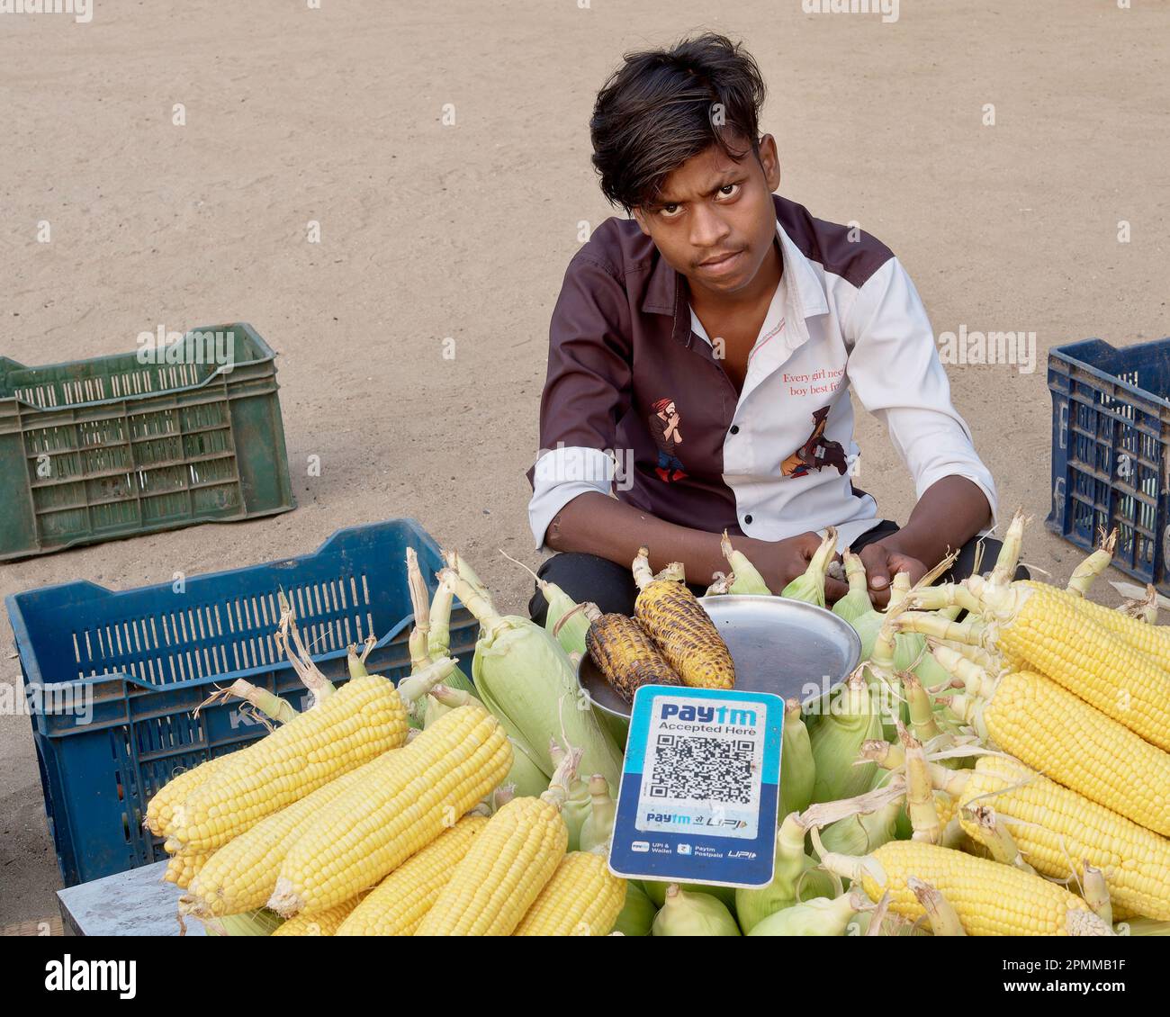 A young Indian man selling roasted corn (maize) at Chowpatty Beach ...