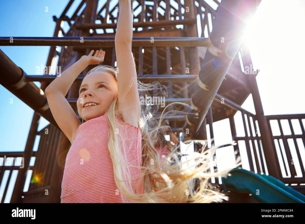 Make some time for play. a little girl hanging on the monkey bars at the playground. Stock Photo