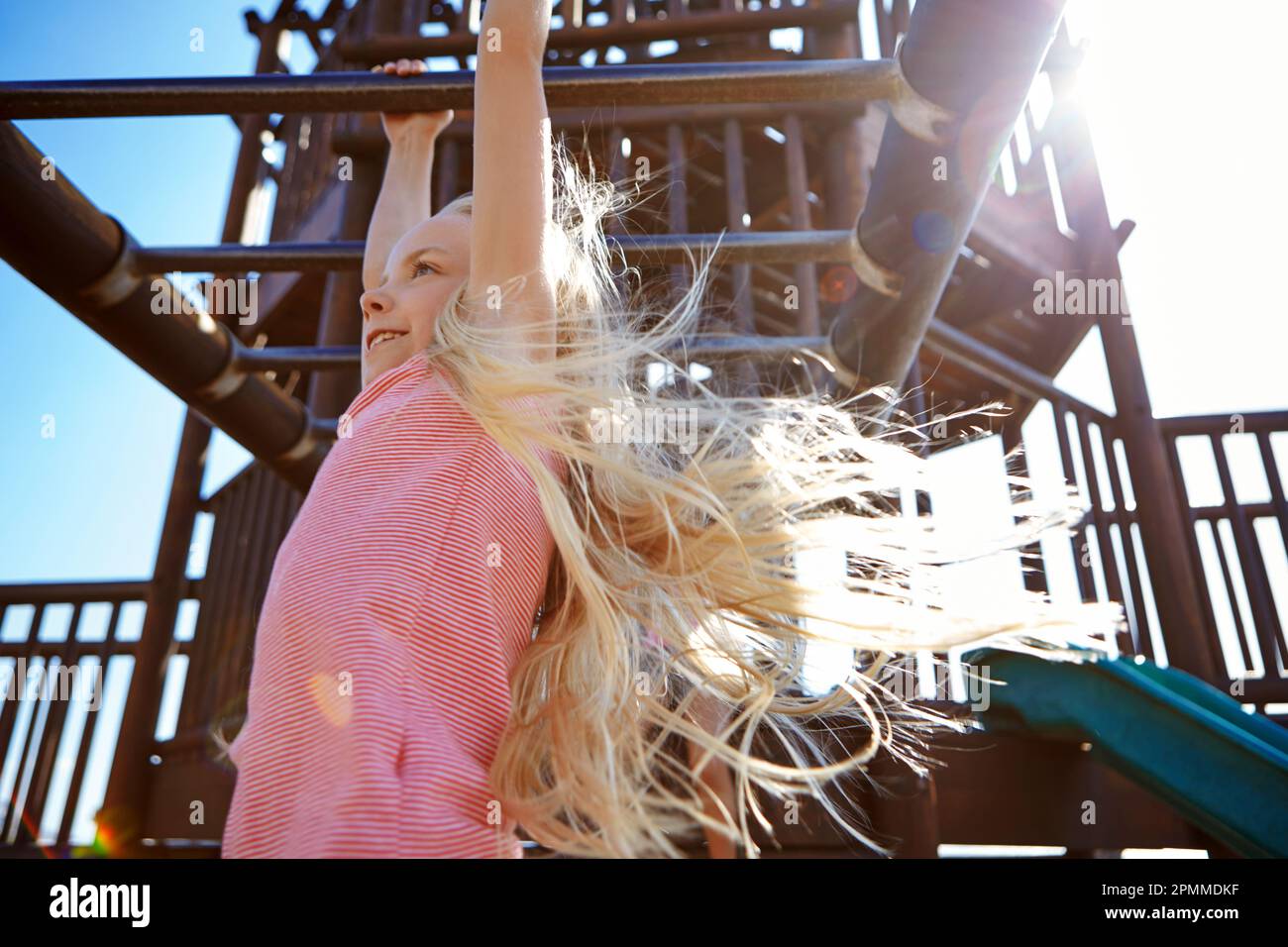 Dont forget to play. a little girl hanging on the monkey bars at the playground. Stock Photo