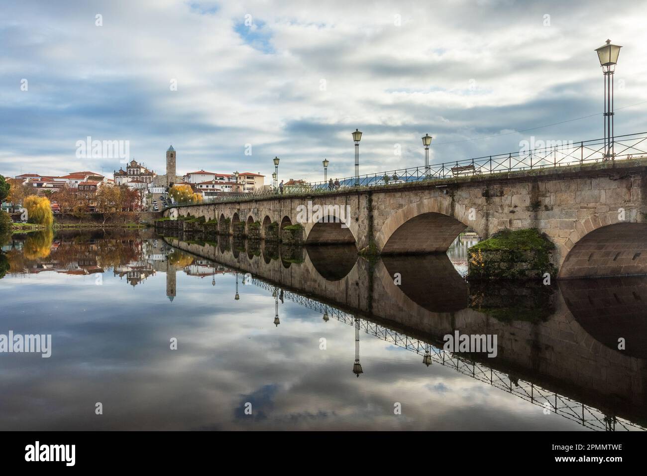 View of the city of Mirandela, Portugal, with the medieval bridge and the Tua river in the foreground, on a misty autumn morning. Stock Photo