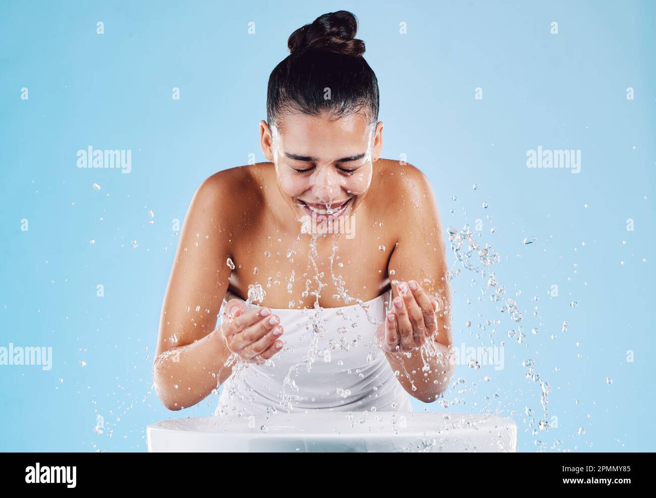 Sink, water splash and happy skincare of a woman washing face for
