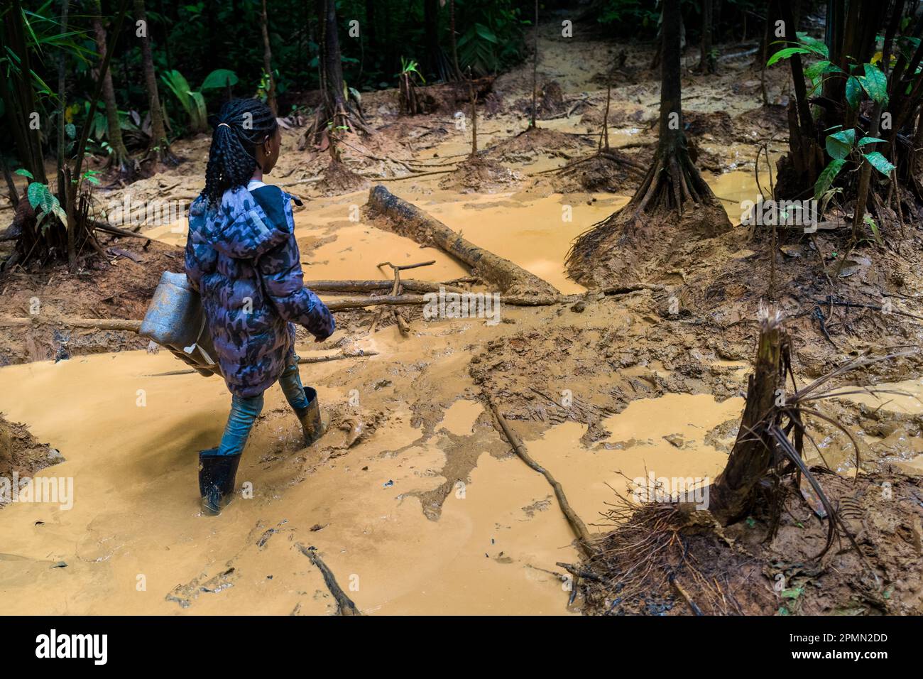A Nigerian migrant child walks through a muddy trail in the wild and dangerous jungle of the Darién Gap between Colombia and Panamá. Stock Photo