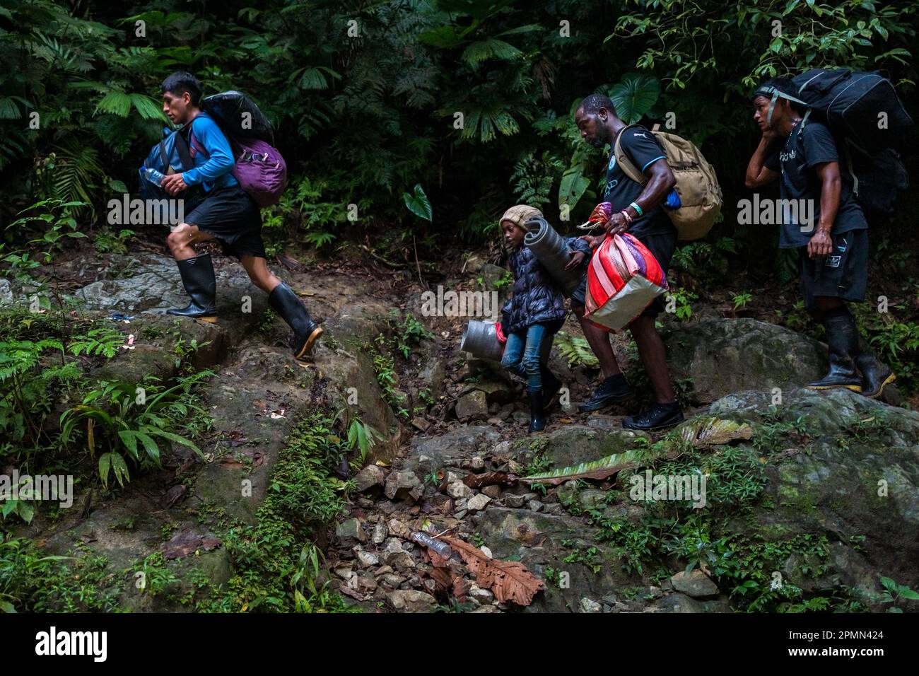 Migrants from Ecuador and Nigeria walk through a rocky trail in the wild and dangerous jungle of the Darién Gap between Colombia and Panamá. Stock Photo