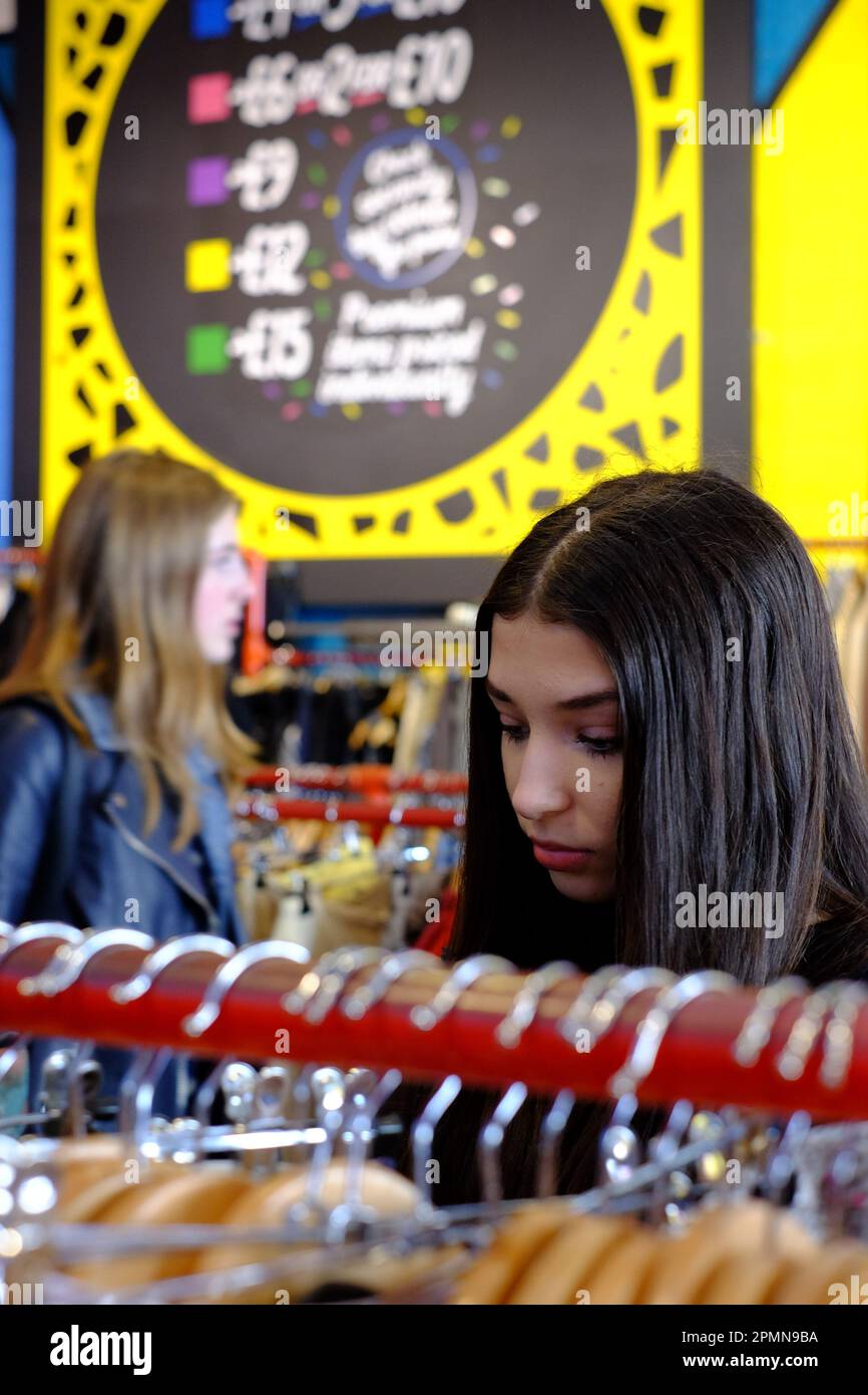 Young woman and teenager shopping in a vintage clothing store for preloved items and style. Stock Photo
