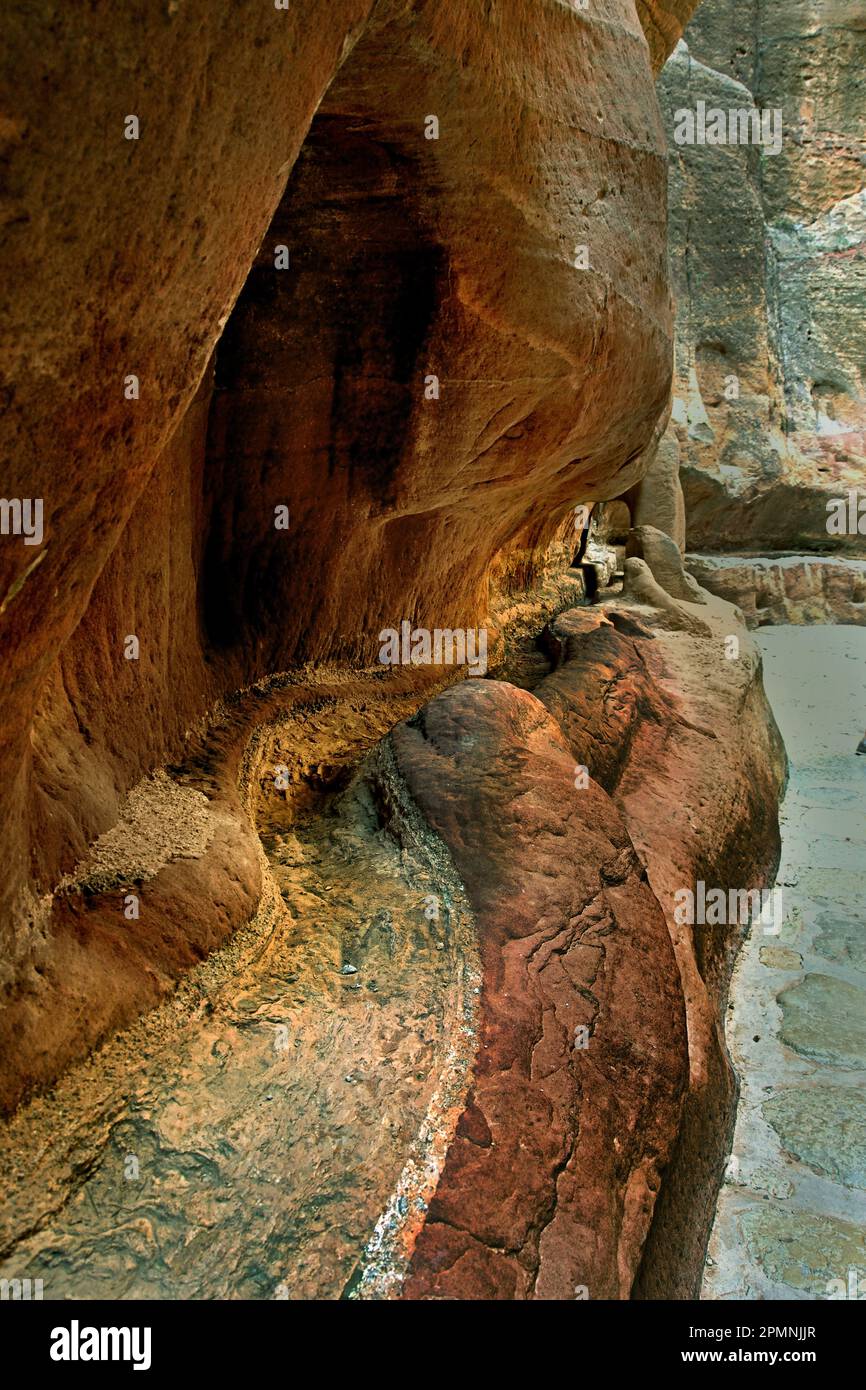 Petra city Nabataean caravan-city rock-cut façades Jordan carved sandstone rock desert. Sculpture covered water channel brings water spring Wadi Musa Stock Photo