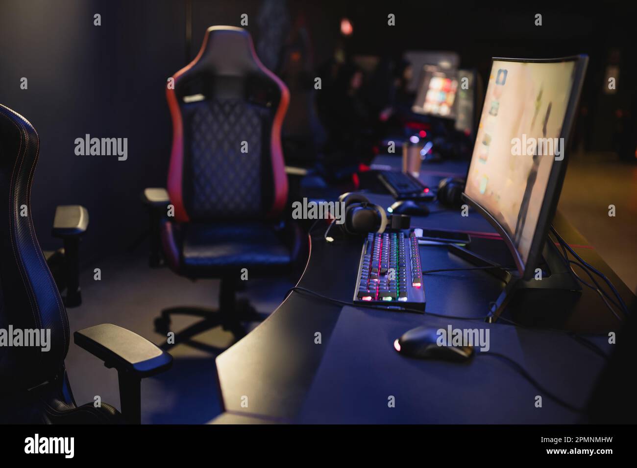 Computer monitors and keyboards on table in blurred gaming club,stock