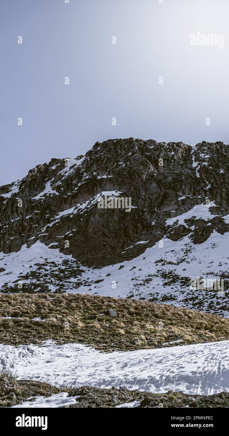 A majestic mountain with a snowy peak and rocky base, blanketed in a ...