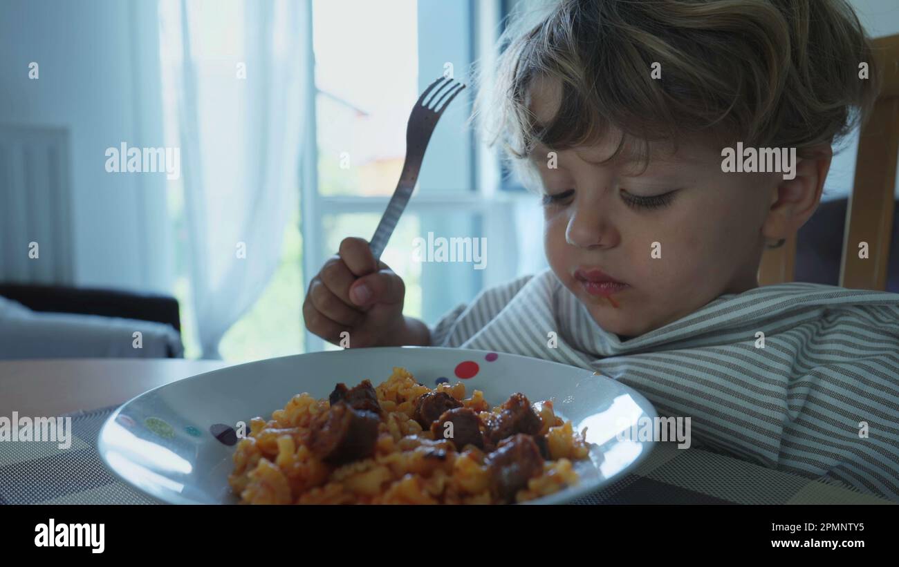 Child eating hot food burning mouth. One small boy spitting pasta out