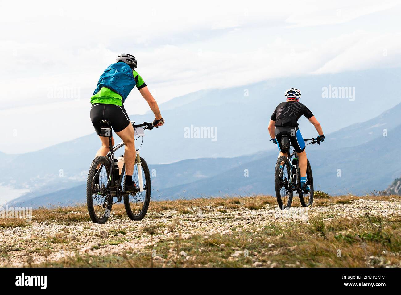 two male mountainbiker riding together sports cycle on mountainous terrain travelling cycling Stock Photo