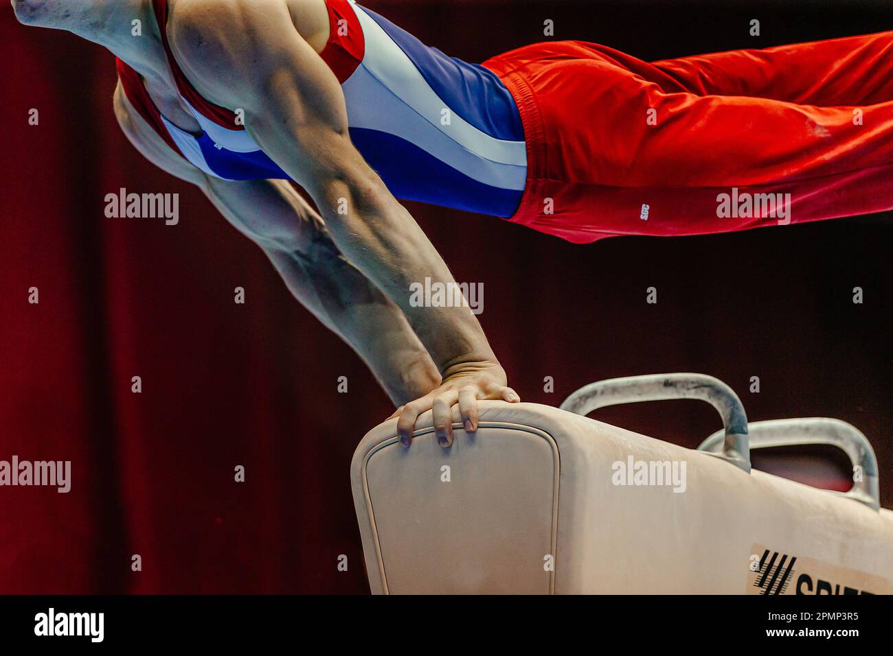 muscular hand male gymnast exercise on pommel horse in gymnastics