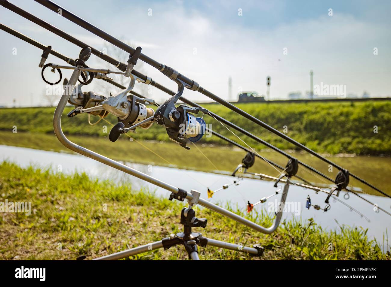 A set of fishing rods and equipment for carp fishing leaning on a tripod on  the riverbank Stock Photo - Alamy