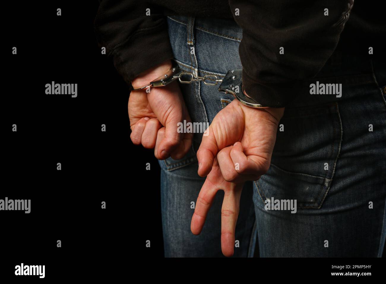 Arrested teenage boy in handcuffs showing just his hands doing a v sign Stock Photo