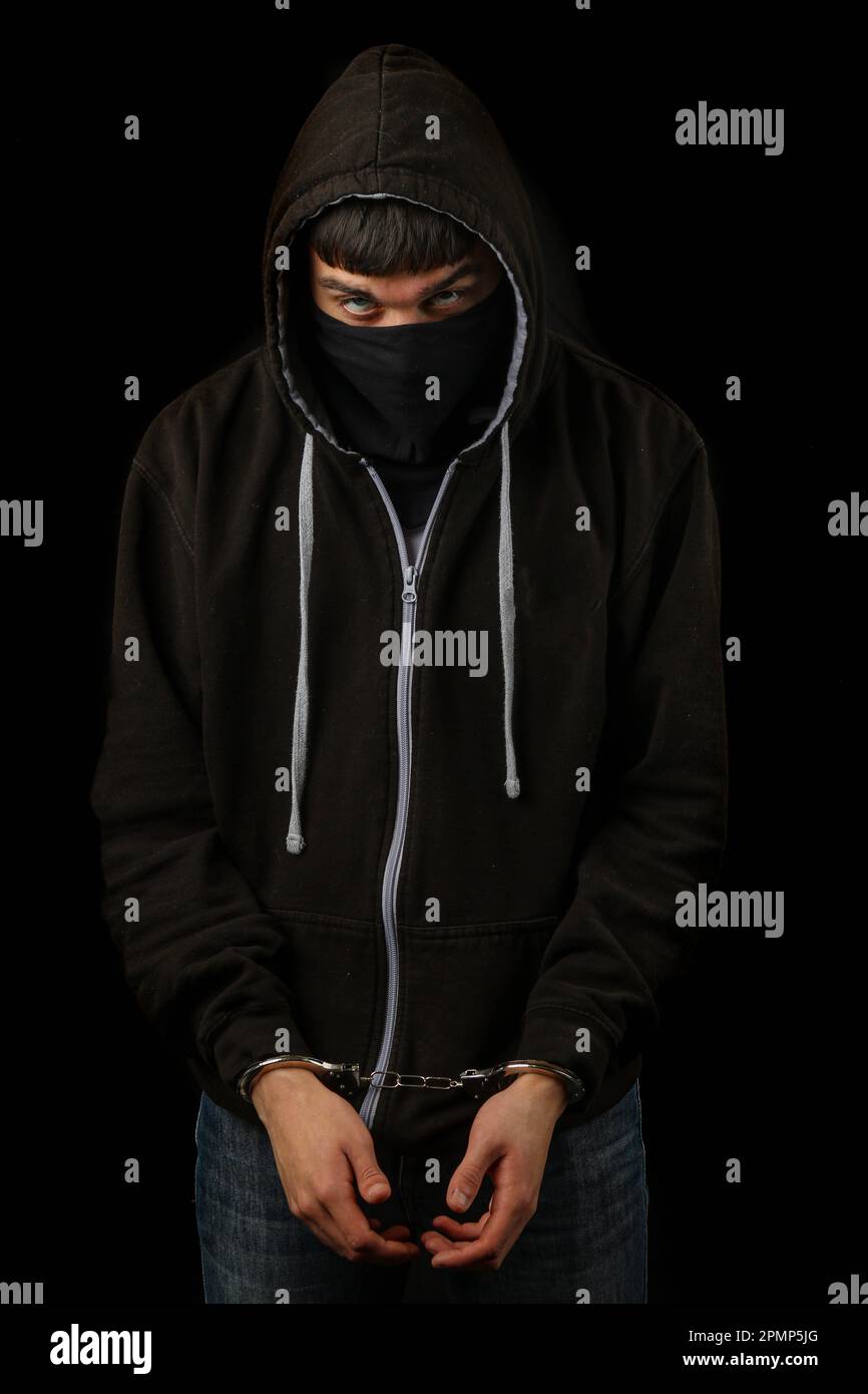 Arrested teenage boy in handcuffs wearing a mask and a hoodie Stock Photo