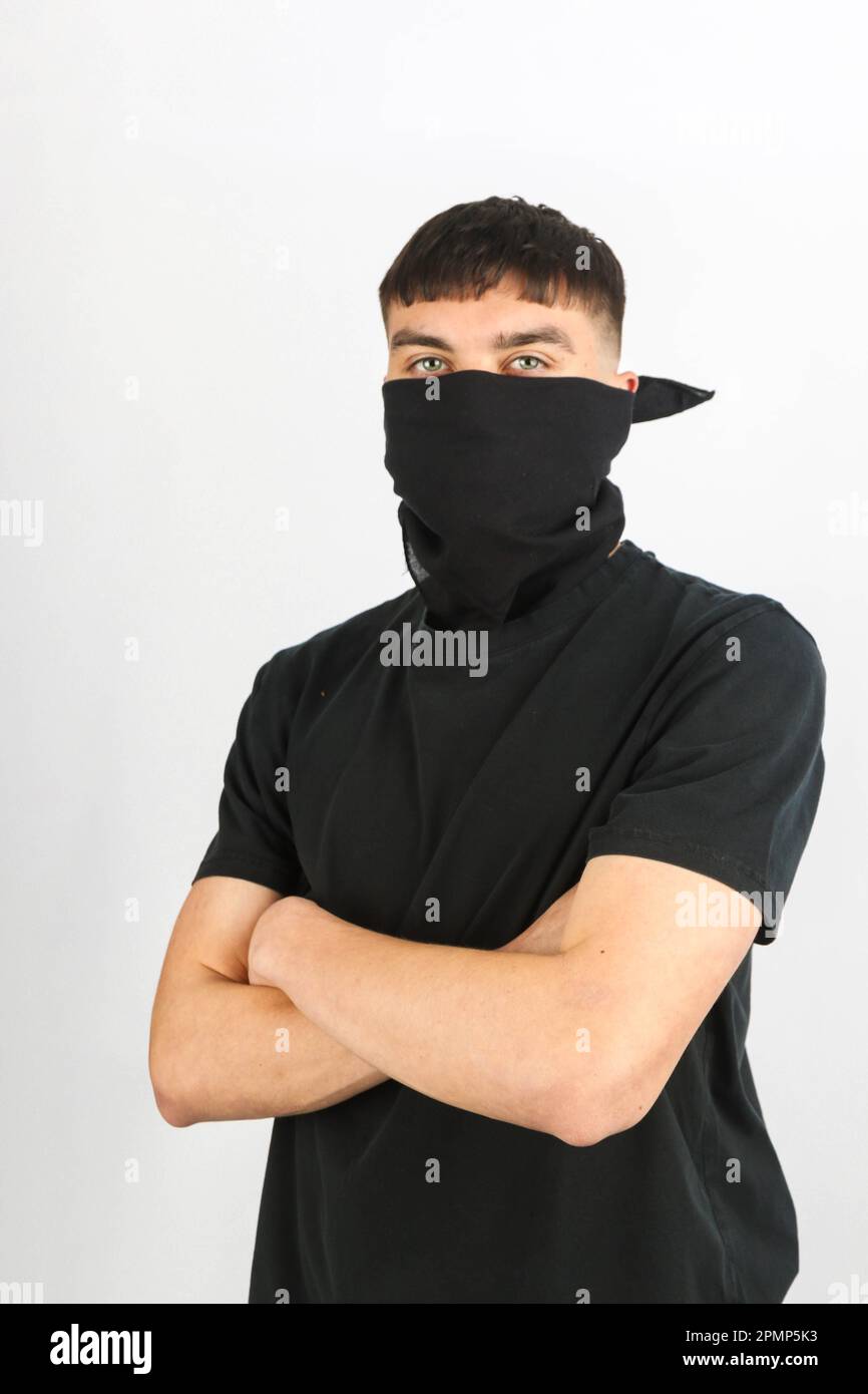 Teenage boy wearing a black mask against a white background Stock Photo