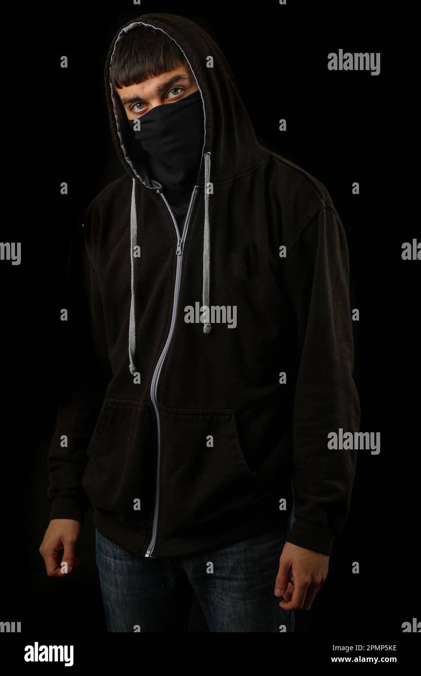 Teenage boy wearing a black mask and black hoodie Stock Photo