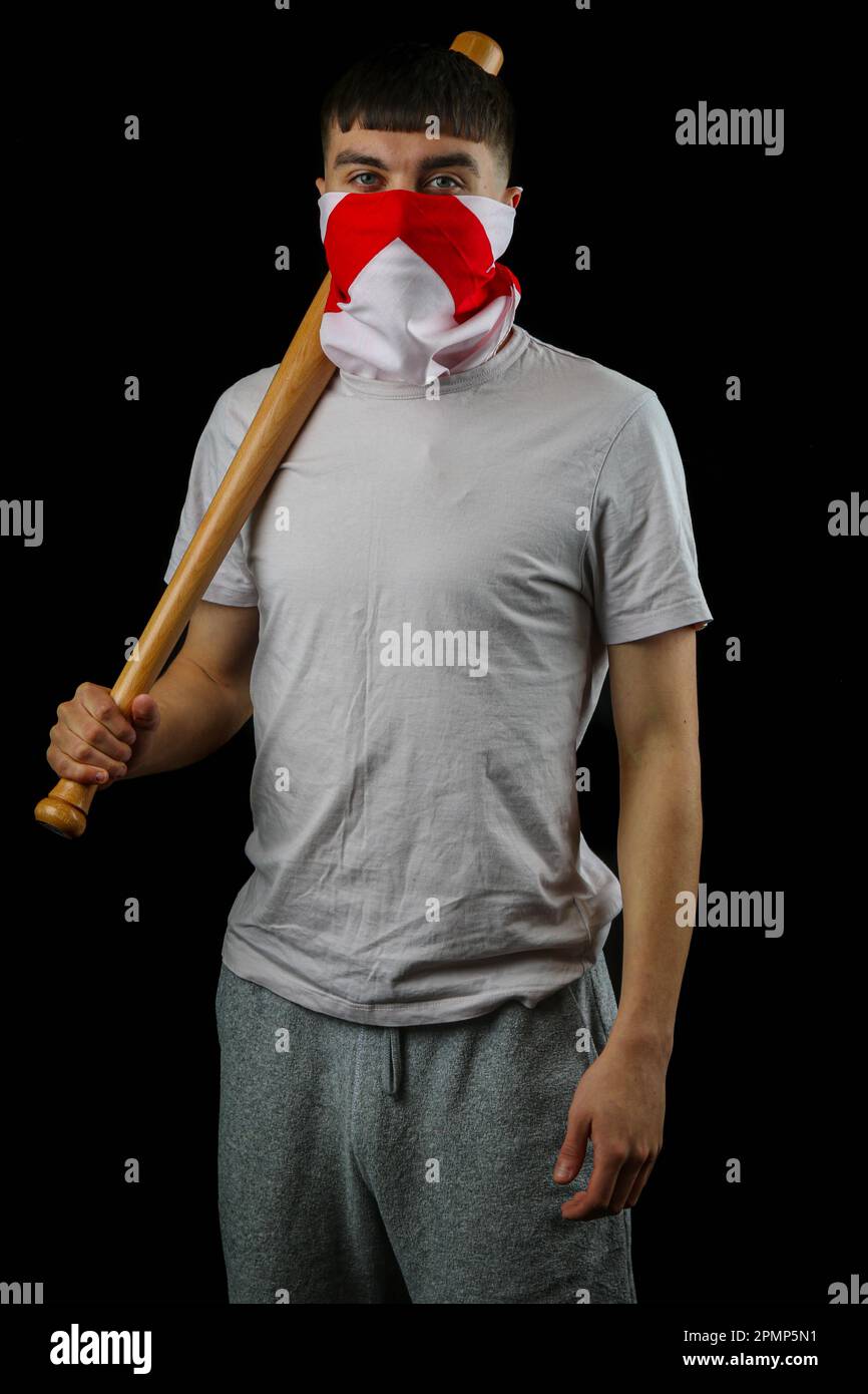 A teenage boy wearing an England flag carrying a baseball bat against a