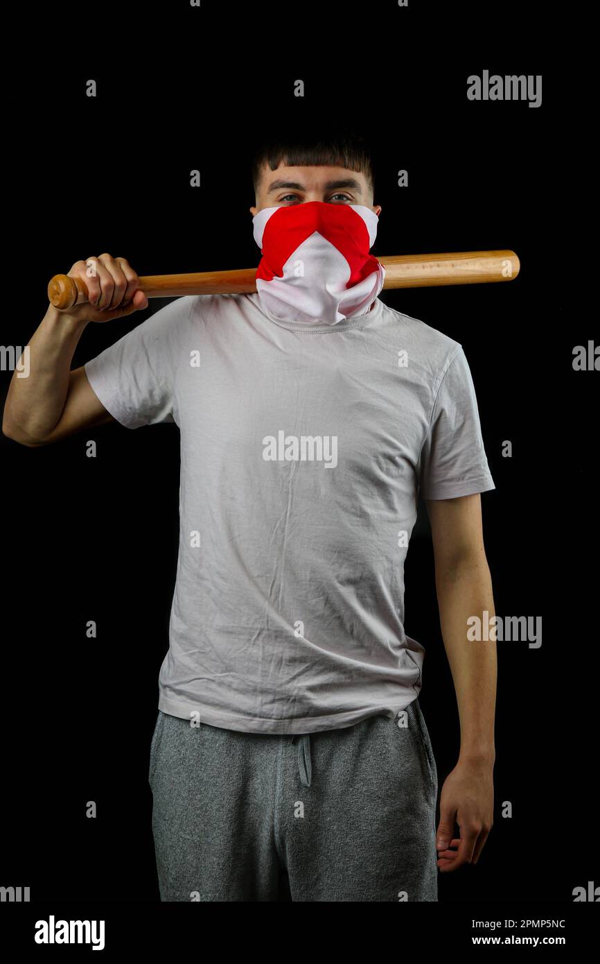 A teenage boy wearing an England flag carrying a baseball bat against a