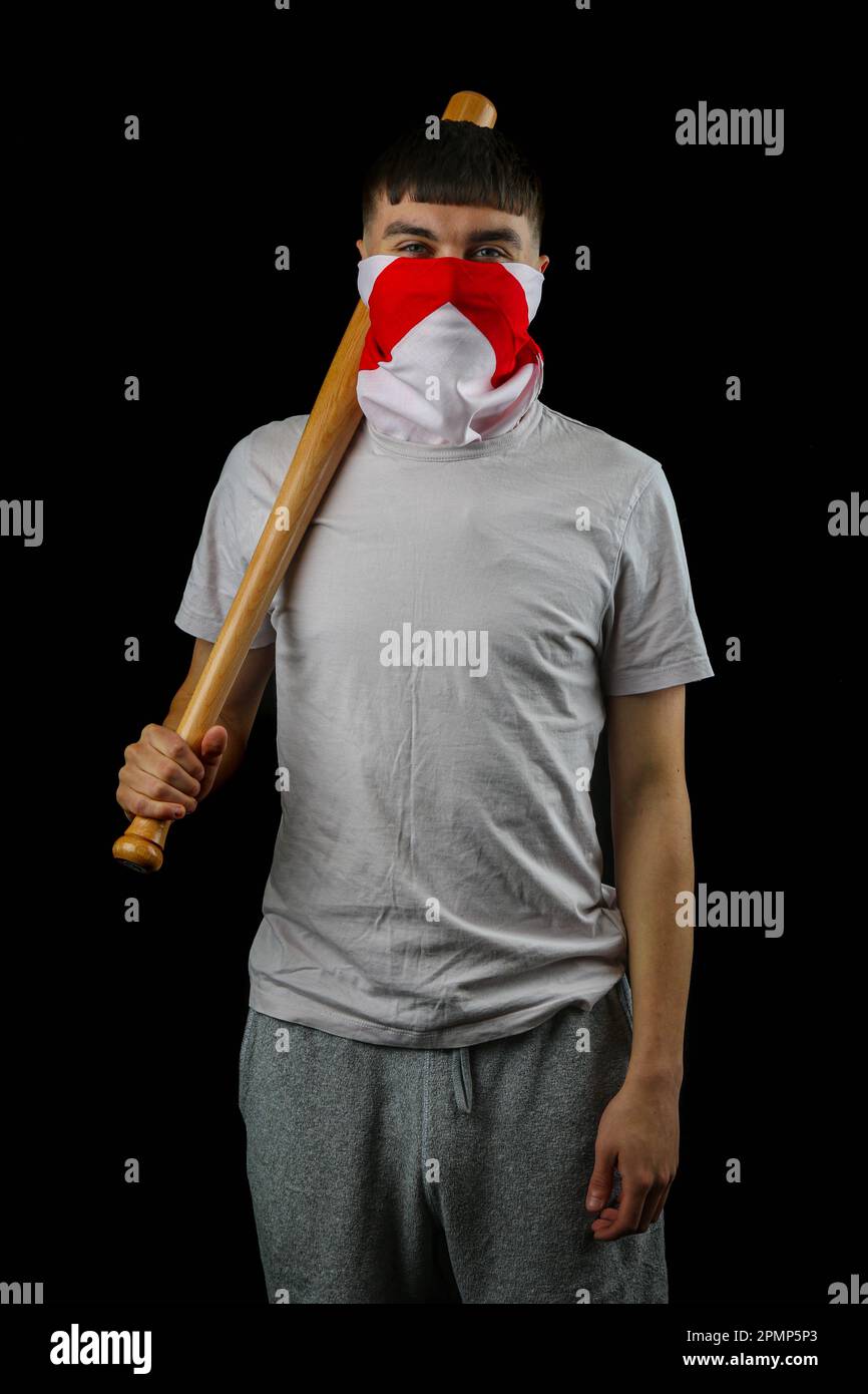 A teenage boy wearing an England flag carrying a baseball bat against a