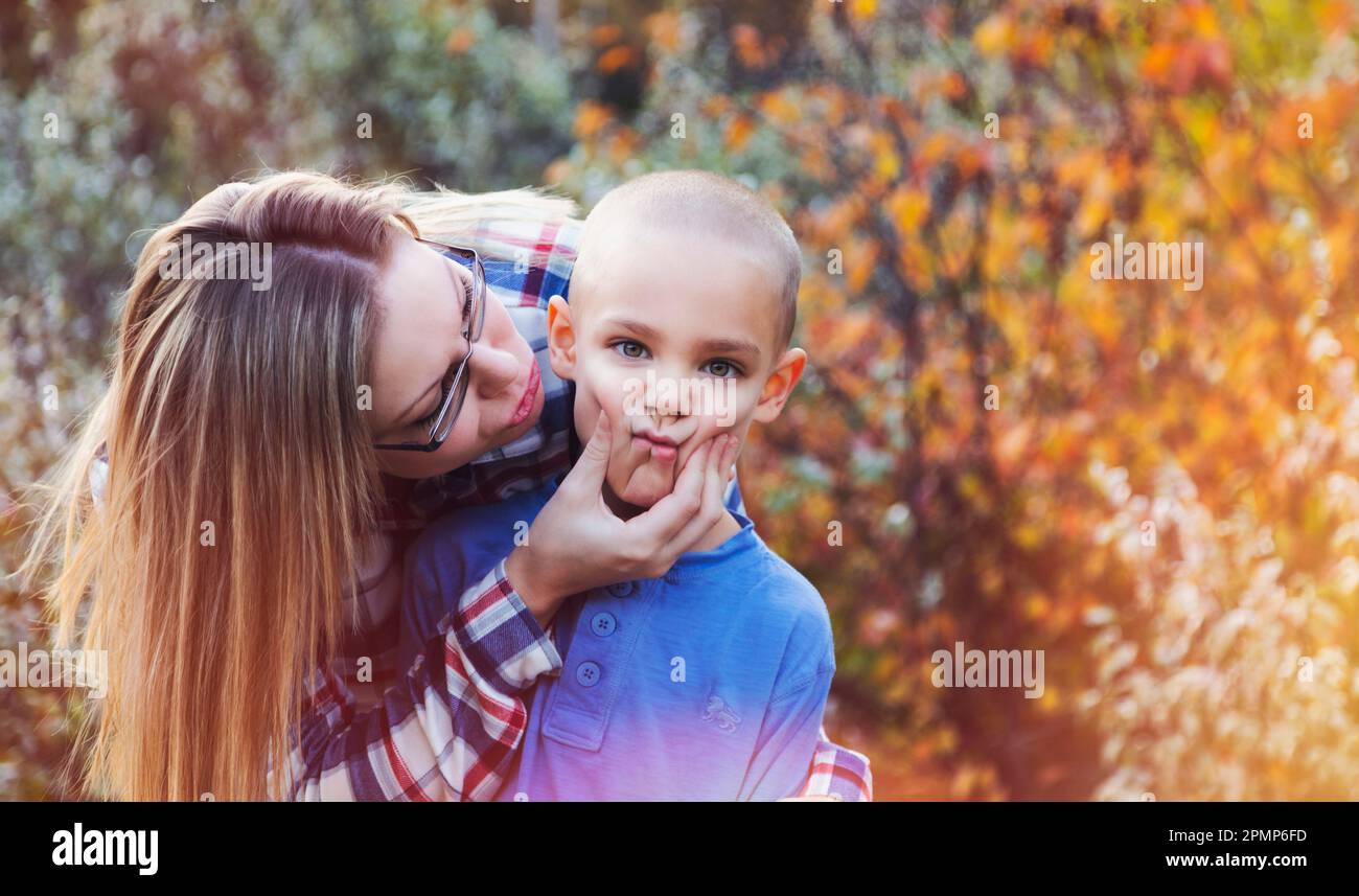 Mother being playful with her son outdoors in autumn, pinching his cheeks in to a funny face; Edmonton, Alberta, Canada Stock Photo