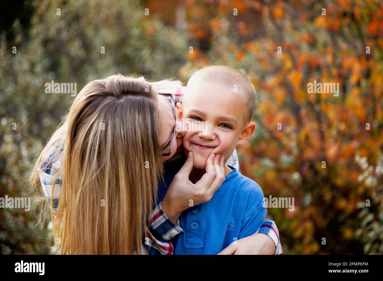 Mother being playful with her son outdoors in autumn, pinching his cheeks in to a funny face; Edmonton, Alberta, Canada Stock Photo