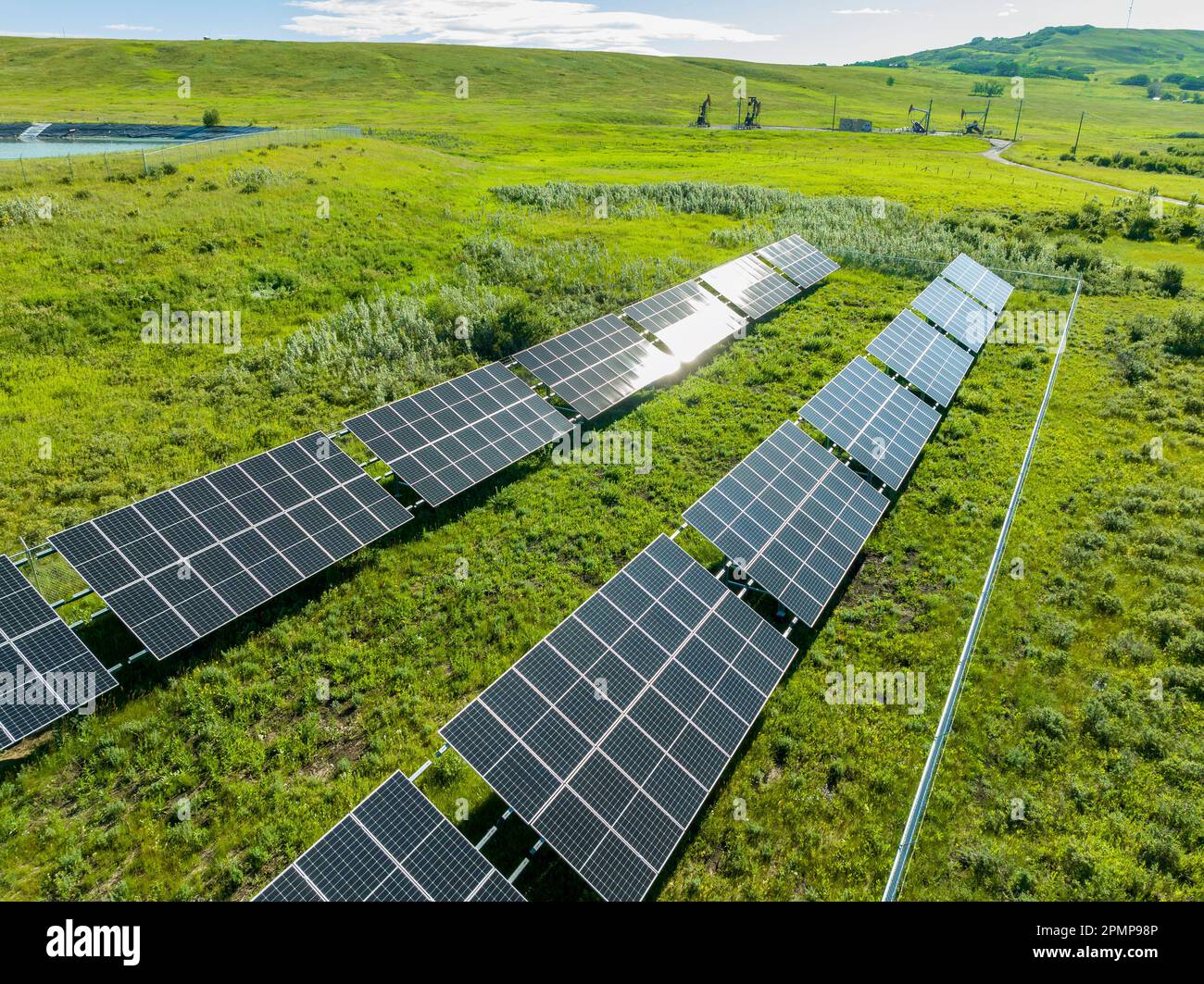 Two rows of solar panels in a green field with rolling hills in the
