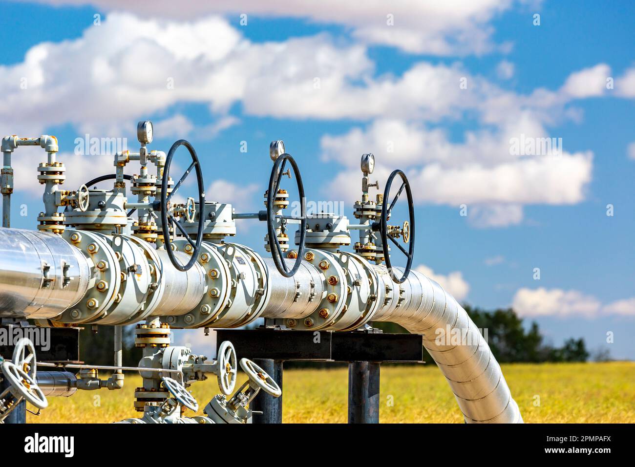 Oil pipeline with values, blue sky and clouds, West of Airdrie; Alberta