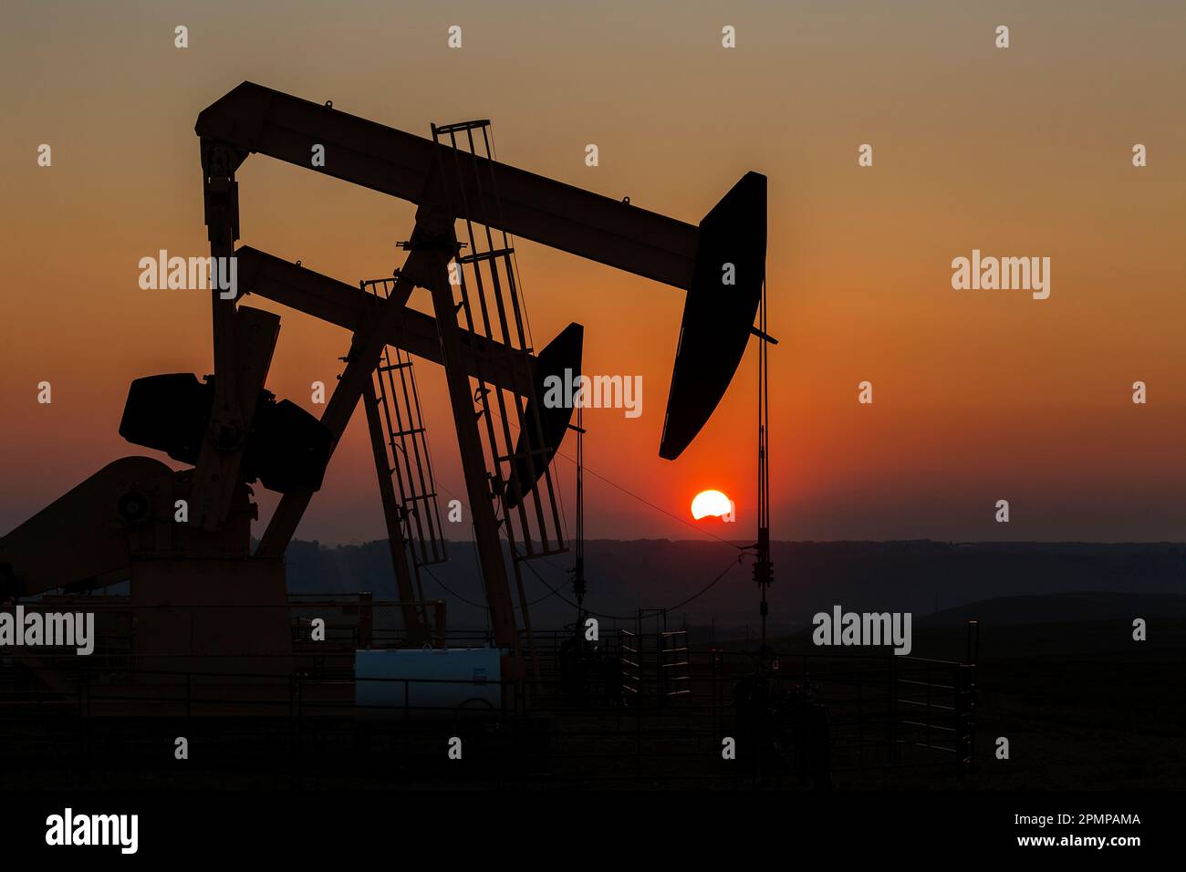 Silhouette of pumpjacks with an orange glowing sky at sunset, West of Airdrie; Alberta, Canada Stock Photo