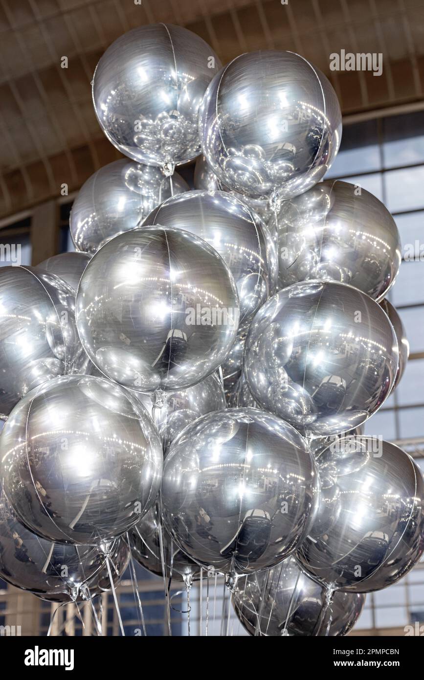 Cluster of Helium Filled Mylar Foil Silver Balloons in Hall Stock Photo