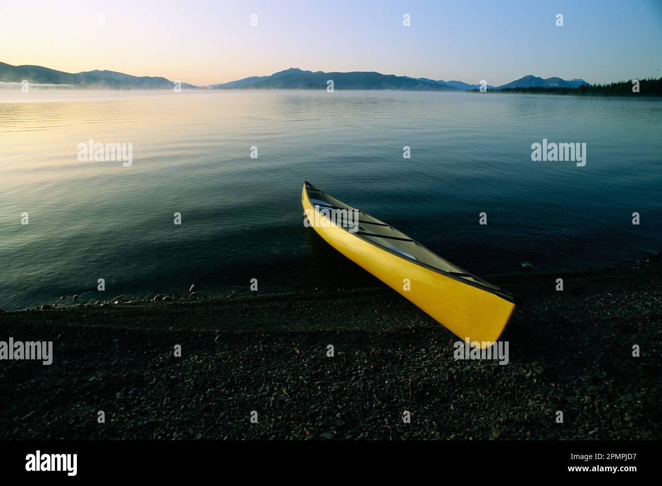 Yellow canoe on the shore of a calm body of water, Kluane Lake, Kluane National Park, Yukon, Canada; Yukon, Canada Stock Photo